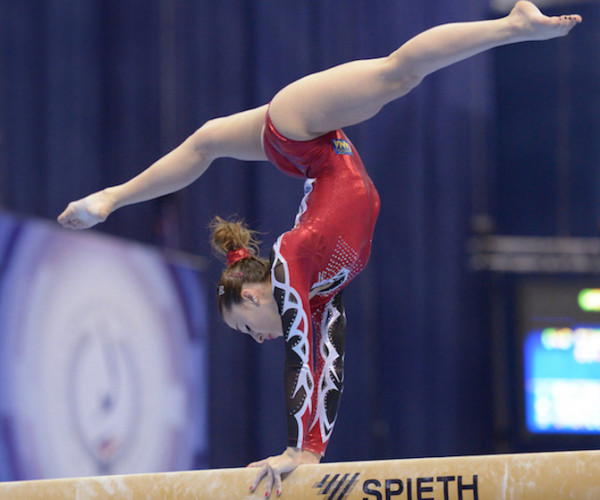 Gymnast doing handstand on the balance beam