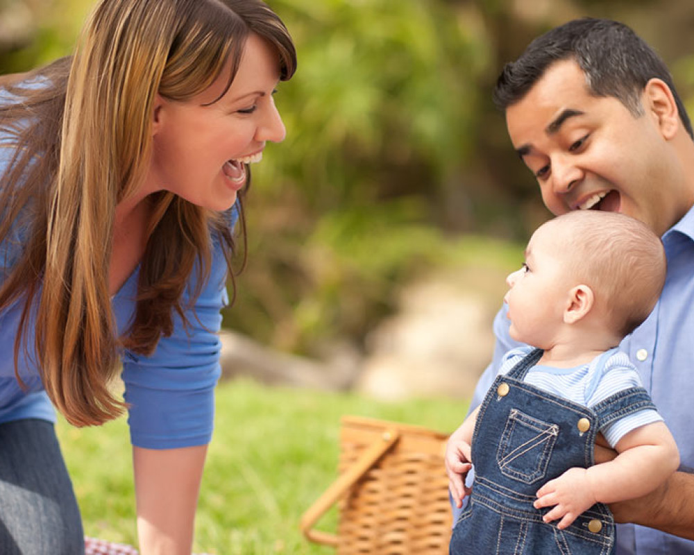 Photo of a mother smiling at baby, held by dad