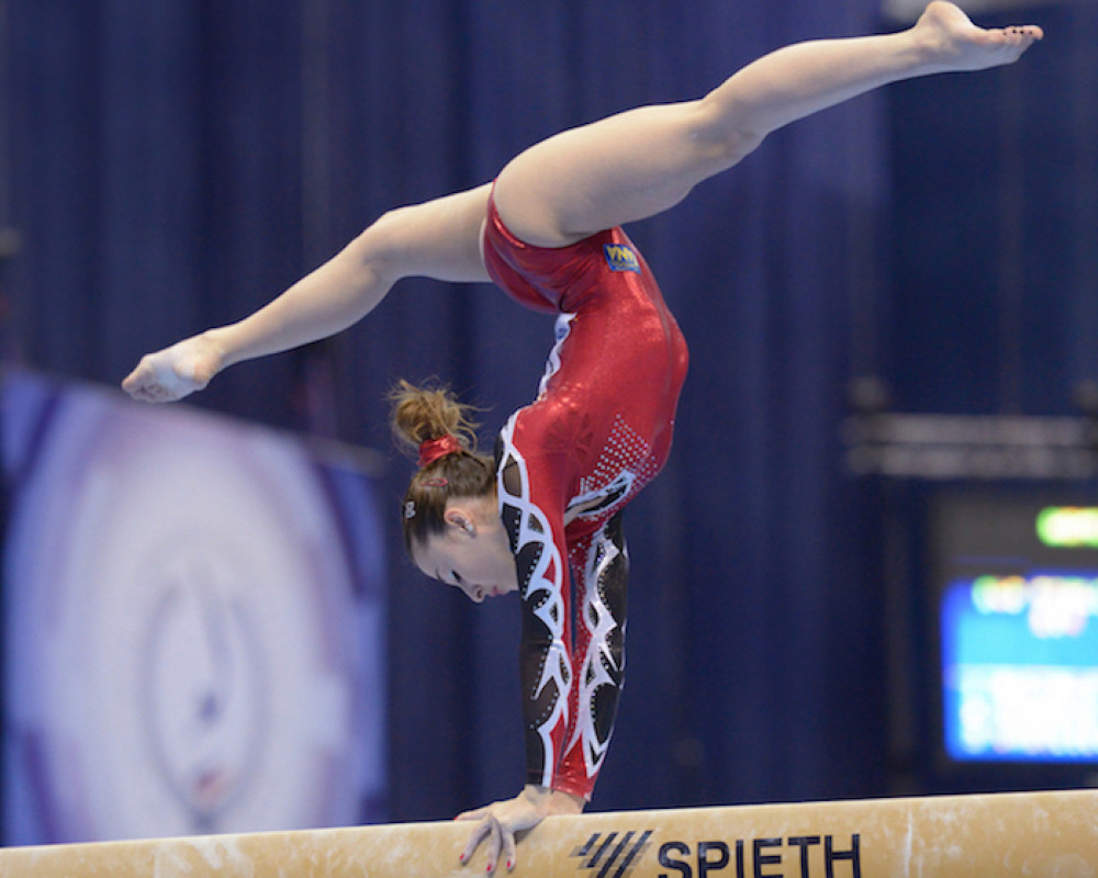 Gymnast doing handstand on the balance beam