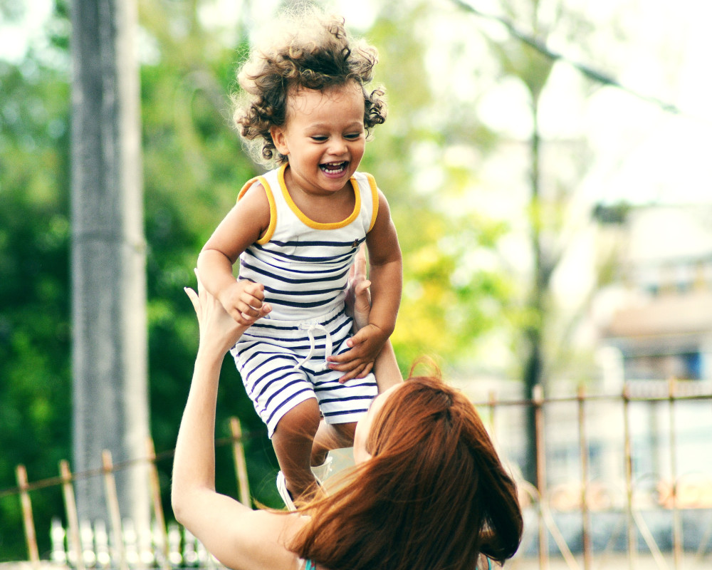 Photo of woman lifting happy child during daytime